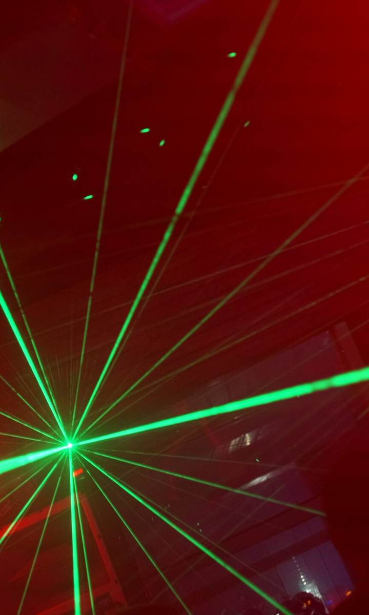 Karanlık kulüpte tek noktadan yelpaze gibi açılan lazer ışınları